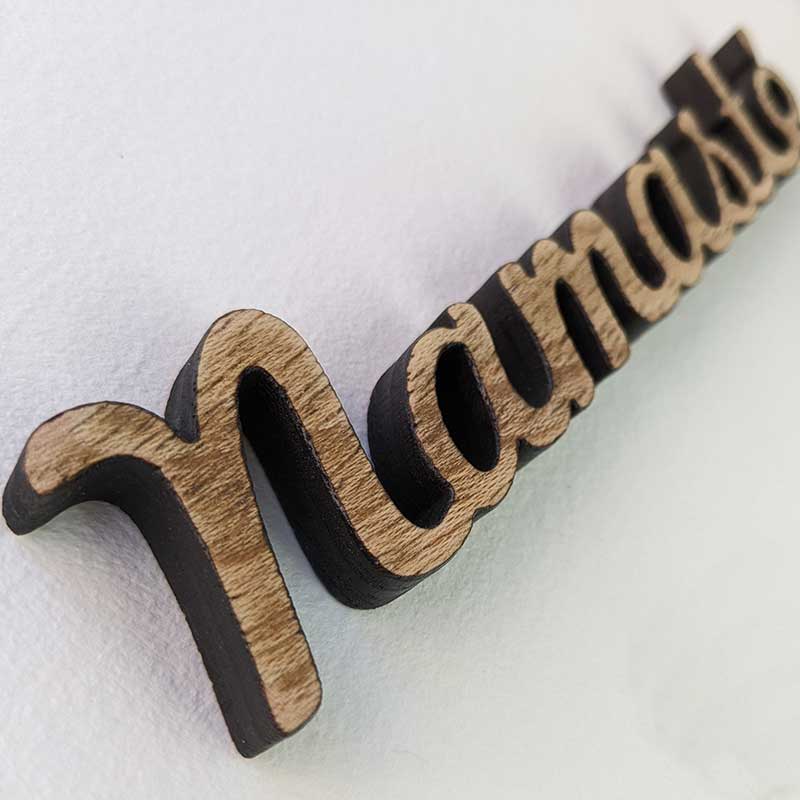 detalle de palabra namasté de madera envejecida sobre fondo blanco