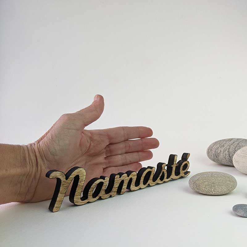 palabra namasté de madera envejecido sobre fondo blanco y palma de una mano para ver tamaño