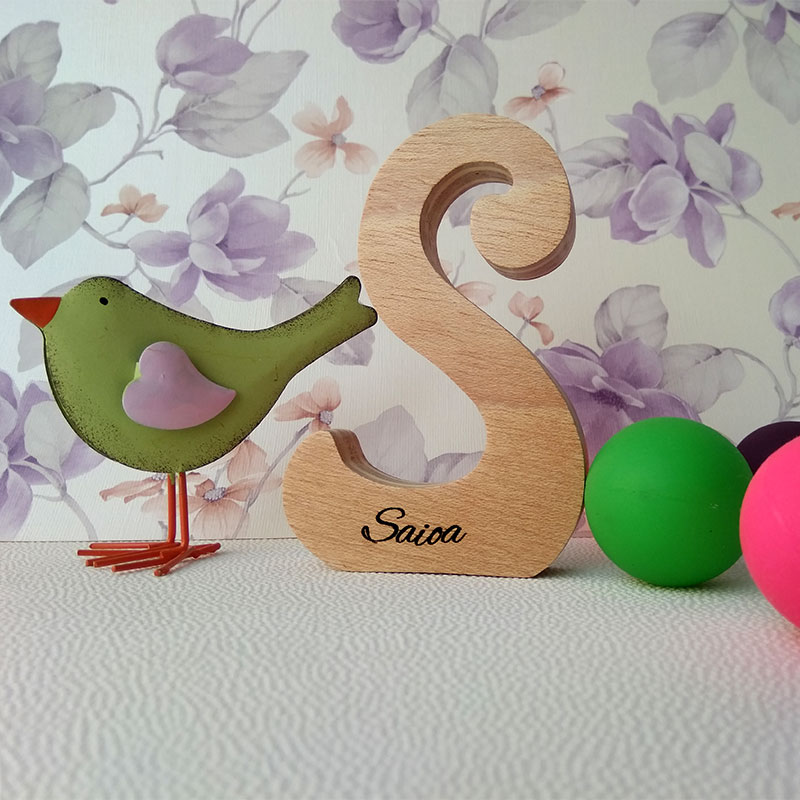 Letra S de madera personalizada con el nombre de Saioa sobre fondo con flores malva y pajarito verde a la izquierda
