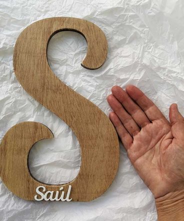 fondo de papel blanco arrugado y mano al lado de letra S de madera decorada con el nombre de Saúl en blanco y en relieve pegado en la parte de abajo