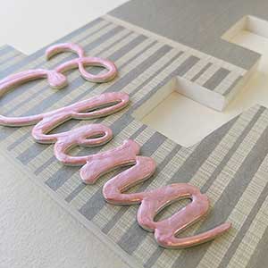detalle de letra E con rayas grises plateadas y nombre en relieve Elena en rosa