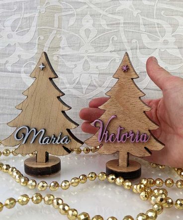dos árboles de navidad de madera sujetos por una mano y personalizados con nombre