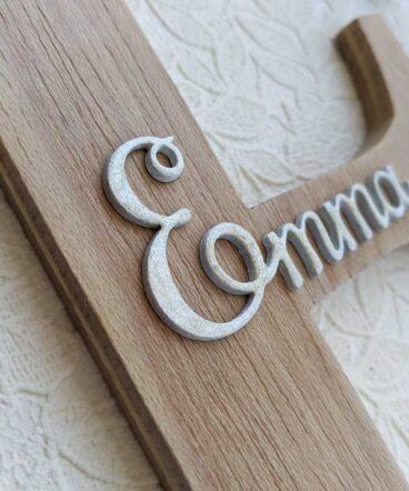 Detallle de Letra E de madera oscura con el nombre de Emma en blanco y en relieve en el centro