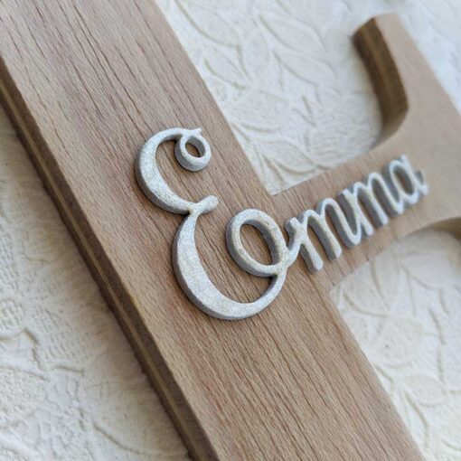 Detallle de Letra E de madera oscura con el nombre de Emma en blanco y en relieve en el centro