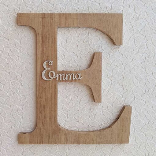 Letra E de madera oscura con el nombre de Emma en blanco y en relieve en el centro