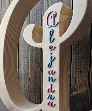 Detalle del nombre de alejandra en azul y fucsia en relieve pegado en letra A de madera