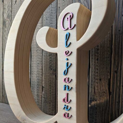 Detalle del nombre de alejandra en azul y fucsia en relieve pegado en letra A de madera