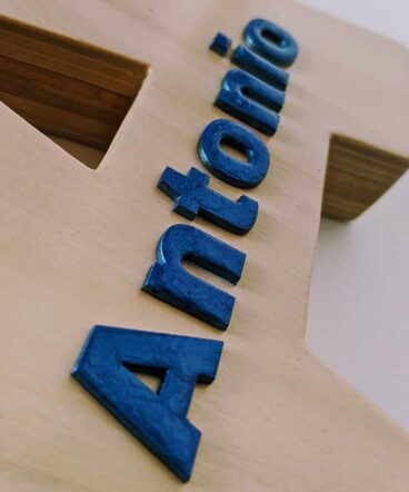 Detalle del nombre de Antonio en relieve color azul y pegado sobre letra A de madera