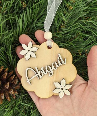 mano sujetando flor de madera de navidad personalizada con el nombre de Abigaíl y flores plateadas