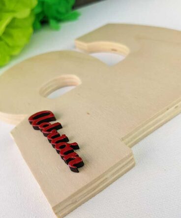 Letra a de madera natural con el nombre de Adrián color rojo y en relieve en la parte baja a la derecha