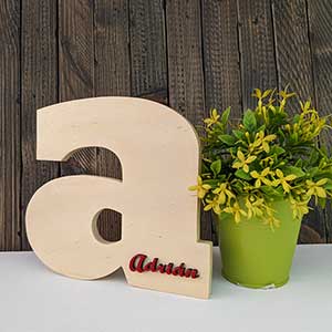 Letra a minúscula de madera natural con el nombre de Adrián color rojo en relieve en la parte abajo