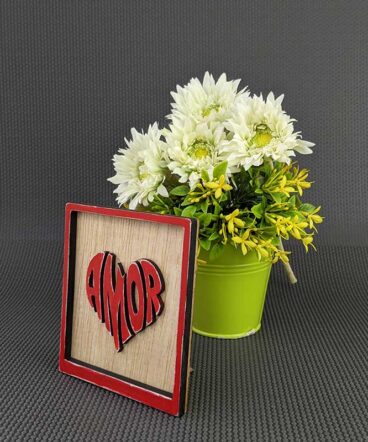 cuadrito de madera con marco y la palabra amor color rojo en el centro con forma de corazón y en relieve