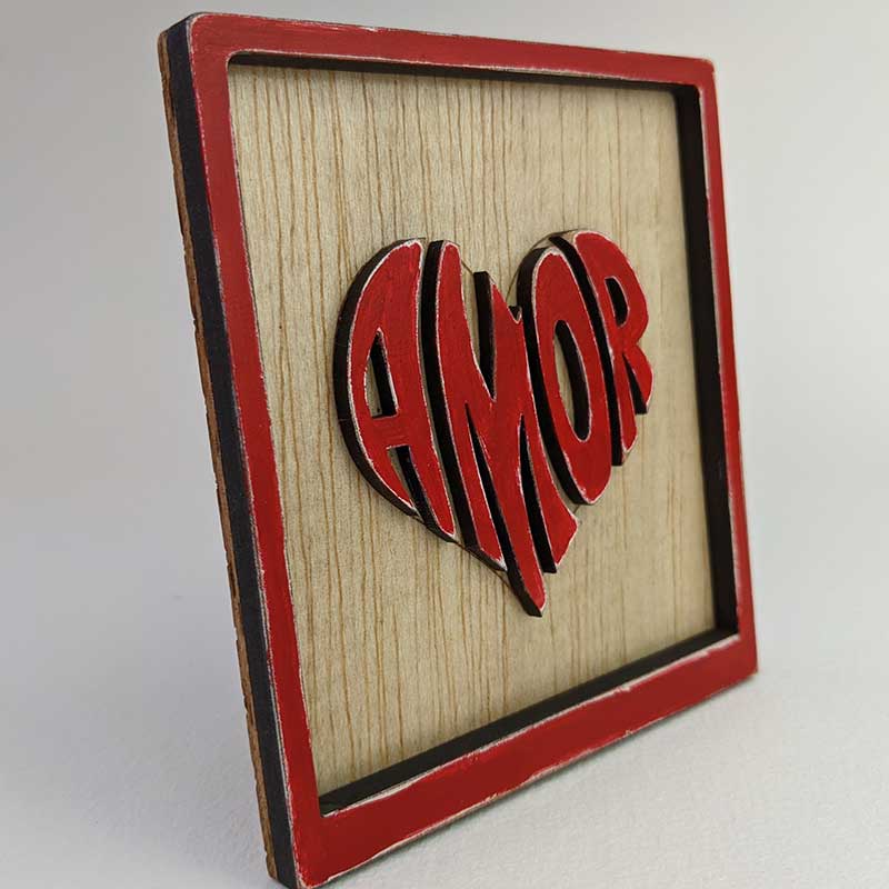 vista lateral de cuadrito con el fondo de madera y con la palabra amor en el centro con forma de corazón y roja