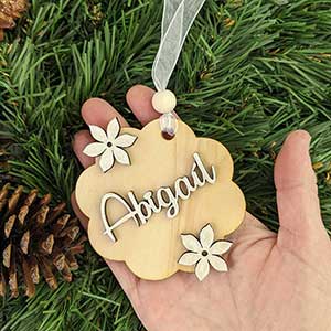 mano sujetando una flor de madera de navidad personalizada con nombre abigaíl y dos flores en relieve color plata