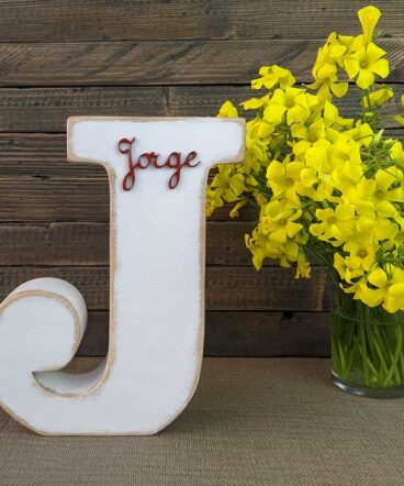 letra j blanca con bordes color madera, con el nombre de Jorge de color rojo y en relieve pegado en la parte de arriba