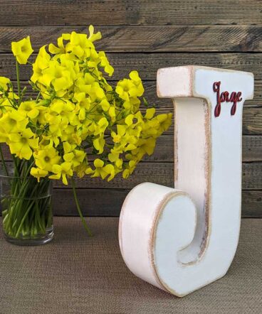 letra j blanca con bordes envejecidos color madera, con el nombre de Jorge de color rojo y en relieve pegado en la parte de arriba