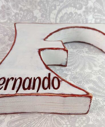 Letra F vista desde abajo color blanco con bordes y nombre Fernando grabado en burdeos