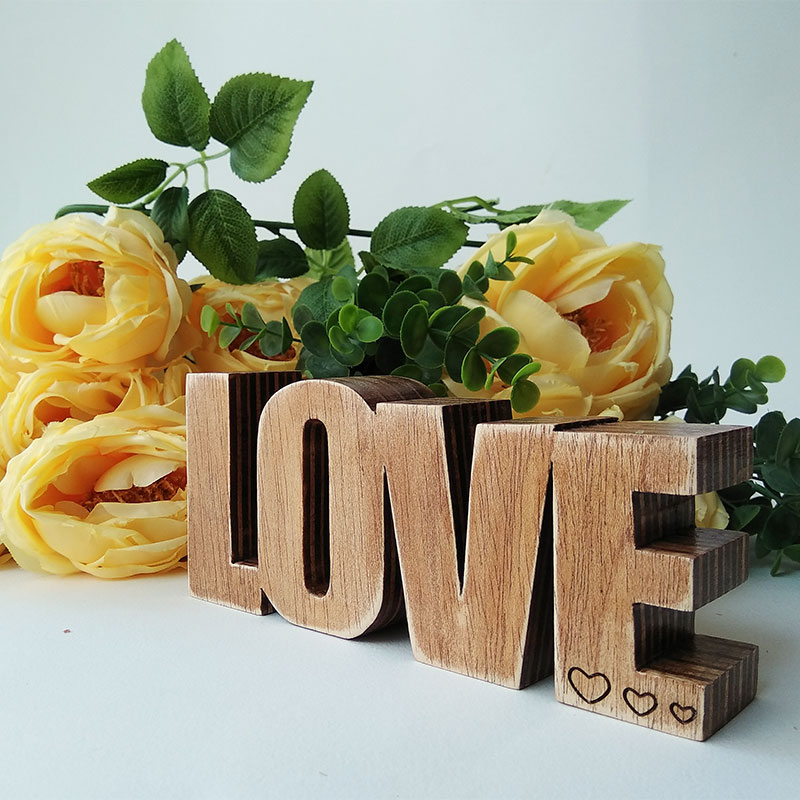 Palabra LOVE vintage hecha de madera natural oscurecida con tres corazoncitos grabados en la E