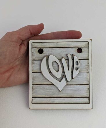 tablero vintage blanco sucio con LOVE en el centro en relieve y con forma de corazón en blanco