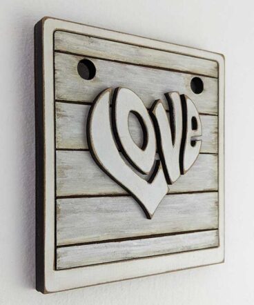 tablero vintage blanco sucio con la palabra LOVE en el centro en relieve y con forma de corazón en blanco