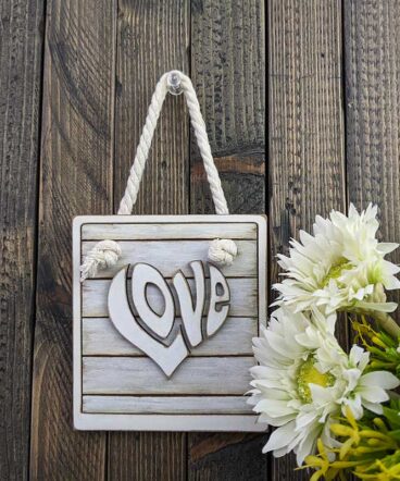 cuadro blanco con la palabra LOVE en el centro en relieve y con forma de corazón pintada en blanco vintage
