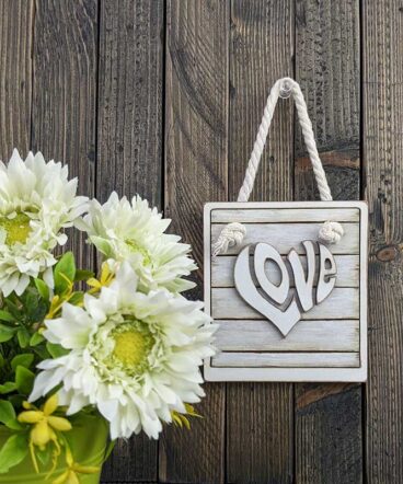 tablero vintage blanco con la palabra LOVE en el centro en relieve y con forma de corazón blanco vintage