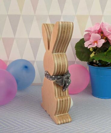 fondo en tonos grises con globos de colores, maceta y conejo de pascua de madera con lazo gris en el cuello