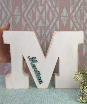 mano sujetando letra M blanca personalizada con nombre martina color turquesa