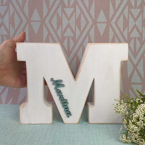 mano sujetando letra M blanca personalizada con nombre martina color turquesa