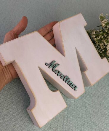 mano sujetando letra M blanca personalizada con el nombre de Martina color azul turquesa