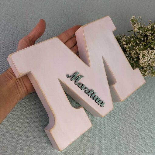 mano sujetando letra M blanca personalizada con el nombre de Martina color azul turquesa