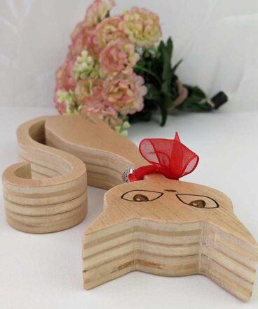 detalle de gato de madera con ojos grabados y lazo rojo en cuello