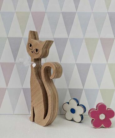 silueta de gato de madera con los ojos grabados y lazo rojo en cuello