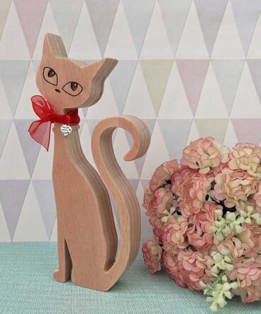 silueta de gato de madera con los ojos grabados y moña roja