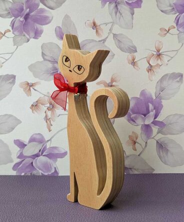 silueta de gato de madera con los ojos grabados y lazo rojo en cuello