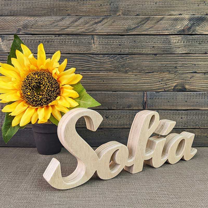 nombre Sofía hecho en madera natural sobre fondo gris y flor amarilla al fondo