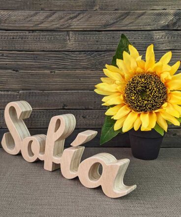 Nombre Sofía hecho en madera natural con fondo gris y flor amarilla al fondo