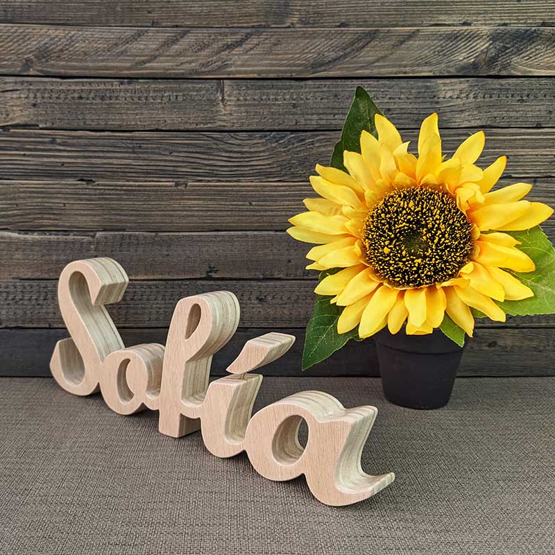 Nombre Sofía hecho en madera natural con fondo gris y flor amarilla al fondo