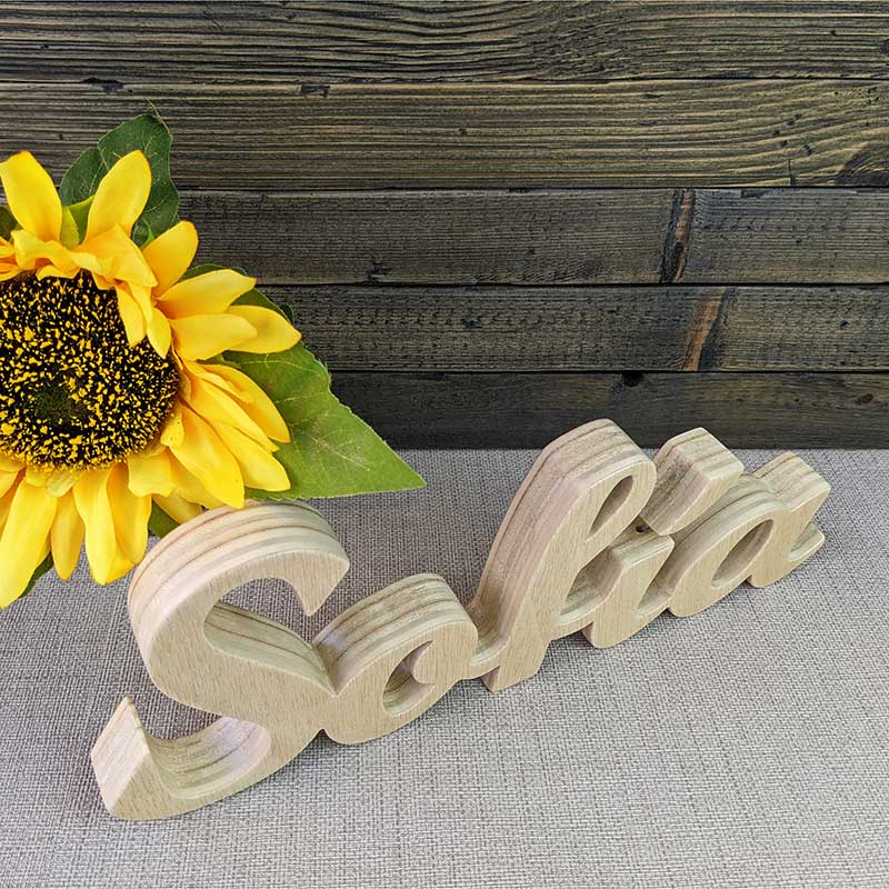 nombre Sofía hecho en madera natural sobre fondo de tablas oscuras y flor amarilla al fondo