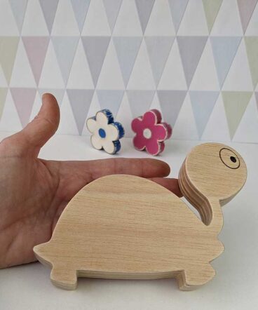 silueta de tortuga de madera sujeta por una mano