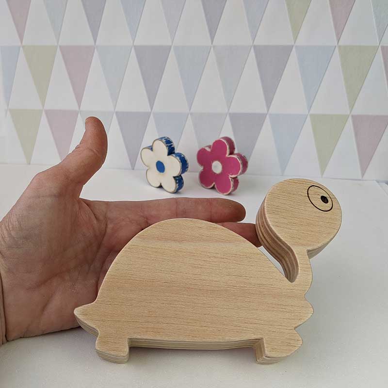 silueta de tortuga de madera sujeta por una mano