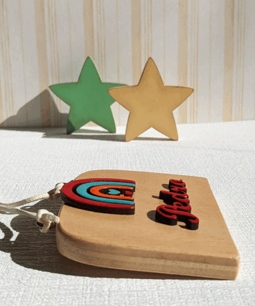 letrero de madera decorado con arcoiris y nombre en rojo